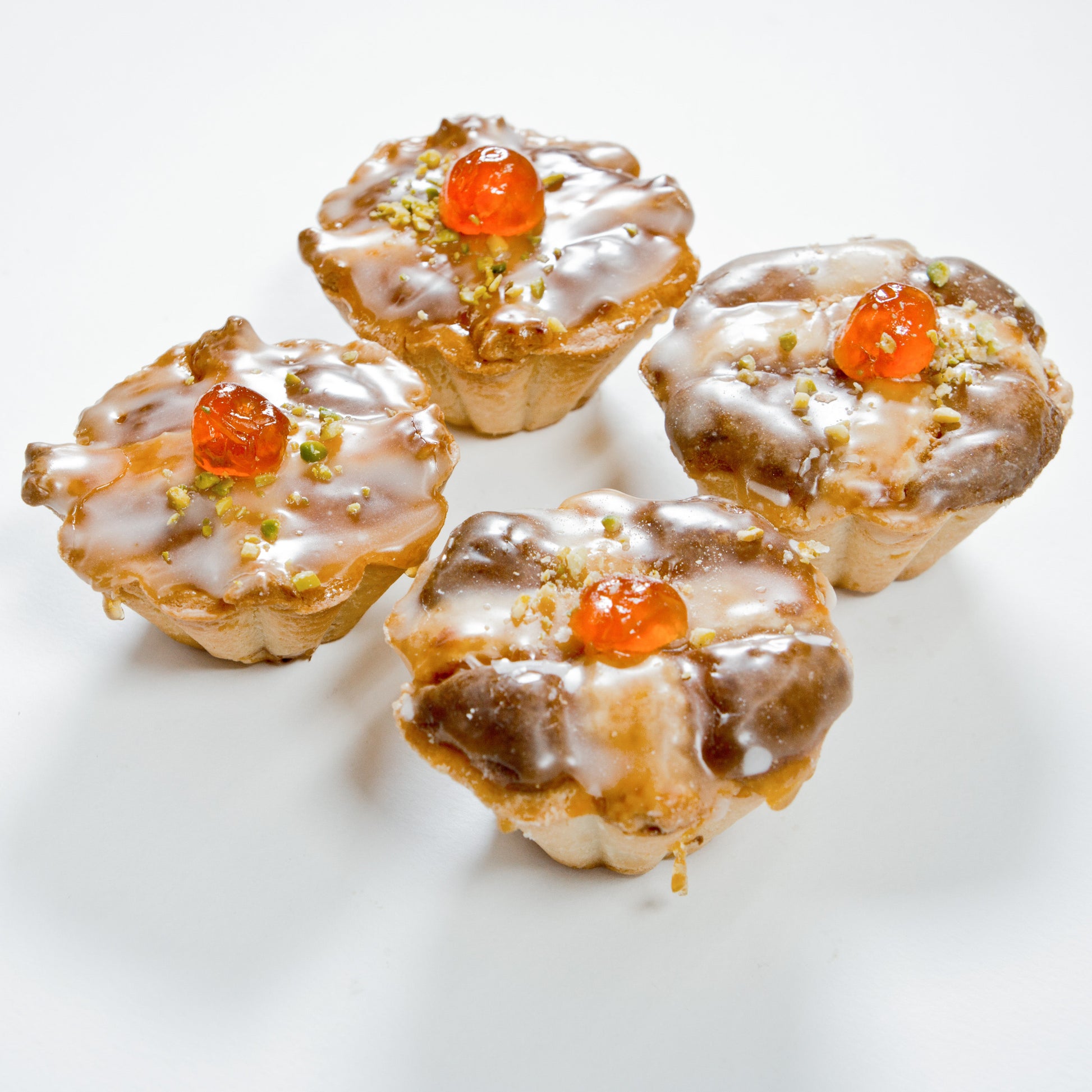 Vier Marzipantörtchen aus feinen Backwaren, appetitlich präsentiert, vom Onlineshop der Bäckerei Sailer.
